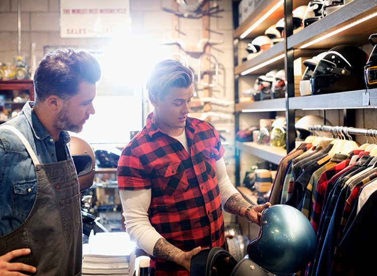 2 males looking at motorcycle gear in a store
